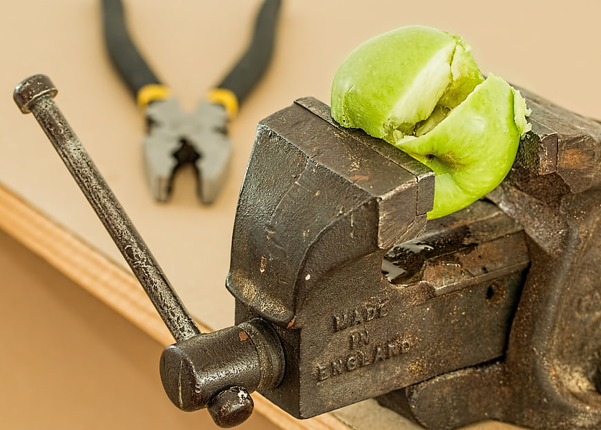 Green apple crushed in a vintage metal bench vise
