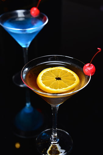 Two elegant cocktails with lemon slice and cherry garnish on black background
