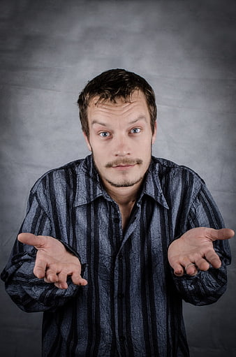 Portrait of a confused man shrugging with open palms