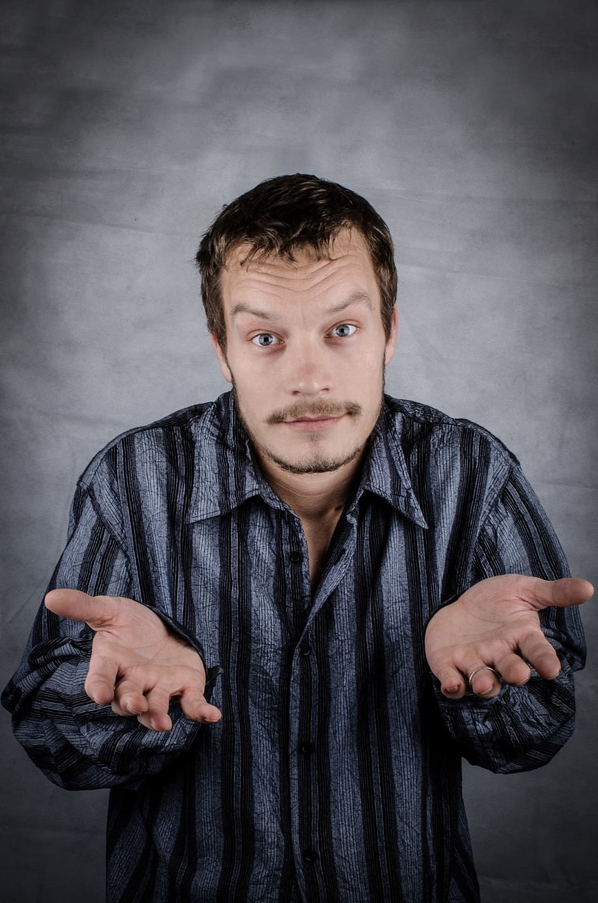 Portrait of a confused man shrugging with open palms