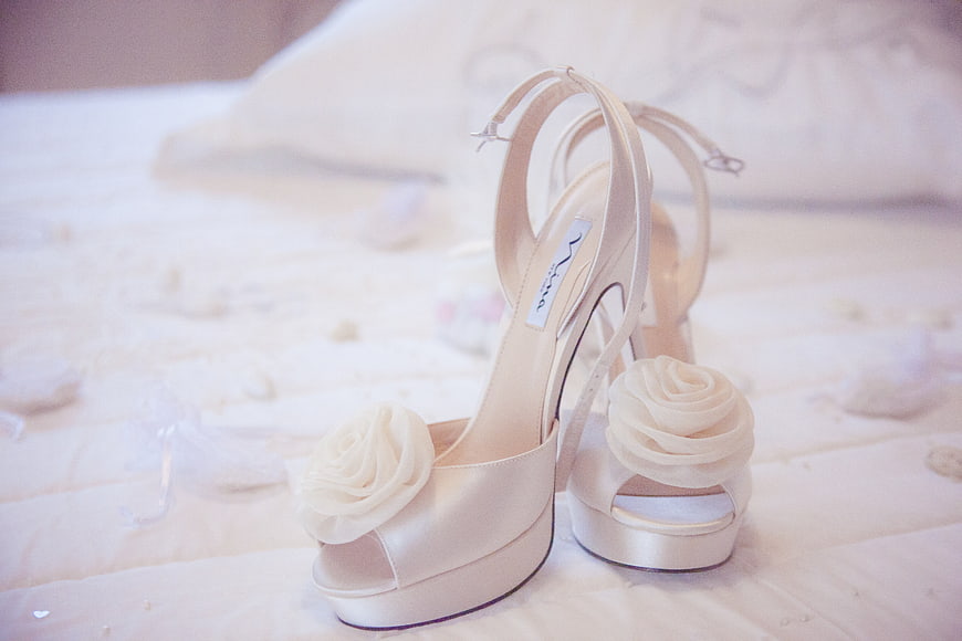 Ivory Satin Wedding Heels With Floral Accents On Bed