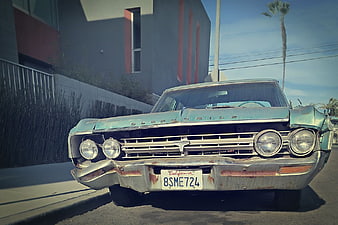 Front view of vintage rusty Oldsmobile parked on street