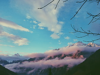 Snowy Mountain Peaks Above Pink Clouds at Sunrise
