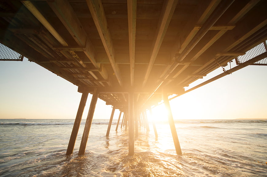 Sunset Under Wooden Pier With Ocean Waves