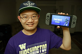 Man holding Nintendo Switch displaying Fortnite game screen