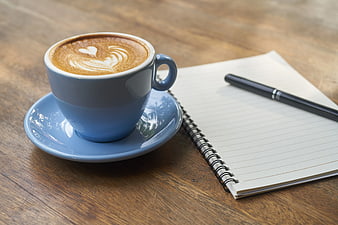 Blue Coffee Cup with Latte Art and Notebook on Wood