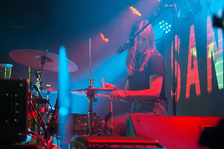 Female Drummer Performing on Stage with Blue and Red Lighting
