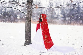 Woman in Red Cape Standing in Snowy Winter Forest