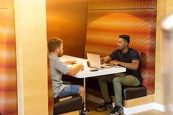 Two Men Working Together in Modern Office Meeting Booth