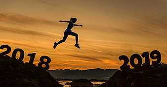 Woman jumping from 2018 to 2019 silhouette at sunset