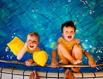 Two happy boys with arm floats in swimming pool