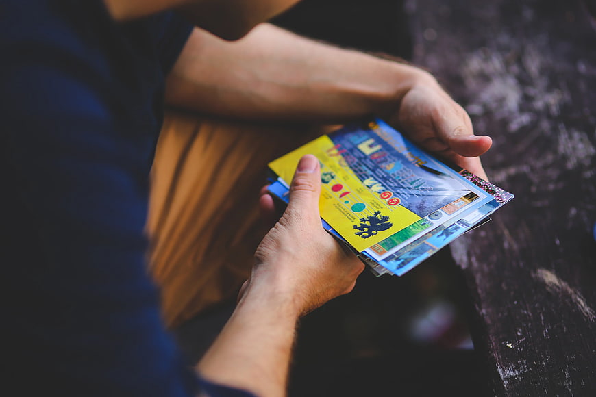 Man holding colorful travel postcards