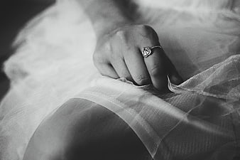Close-up of bride's hand with engagement ring on wedding dress