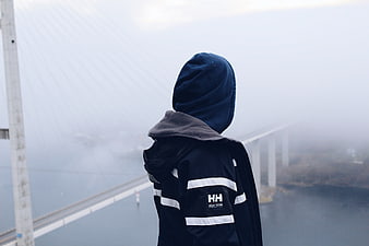 Person in Hoodie Looking at Foggy Suspension Bridge