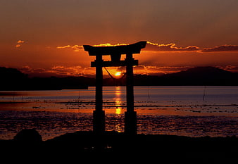 Silhouette of Japanese Torii Gate at Sunset Over Water