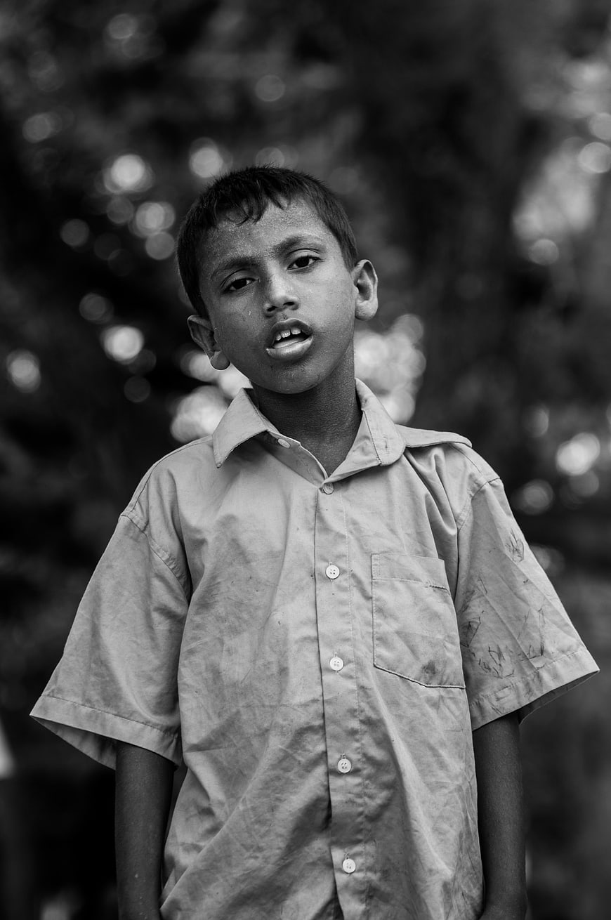 Black and white portrait of a young boy in a worn shirt