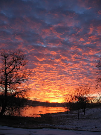 Vibrant orange and purple sunset over snowy river landscape