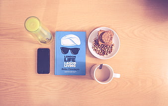 Flat lay of book, coffee, and snacks on wooden table