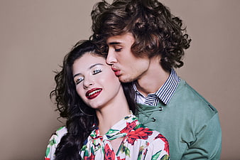 Romantic couple with love text on eyelids kissing cheek