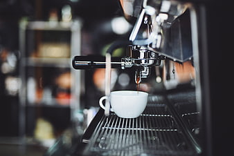 Espresso pouring into white cup from machine