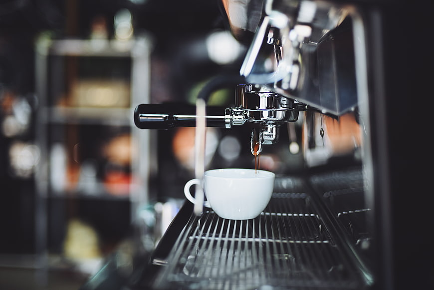 Espresso pouring into white cup from machine