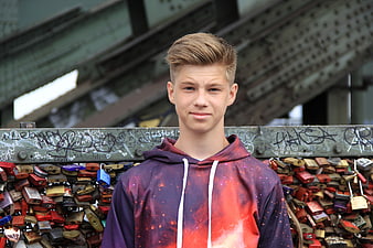 Teenage boy portrait in front of love locks on bridge
