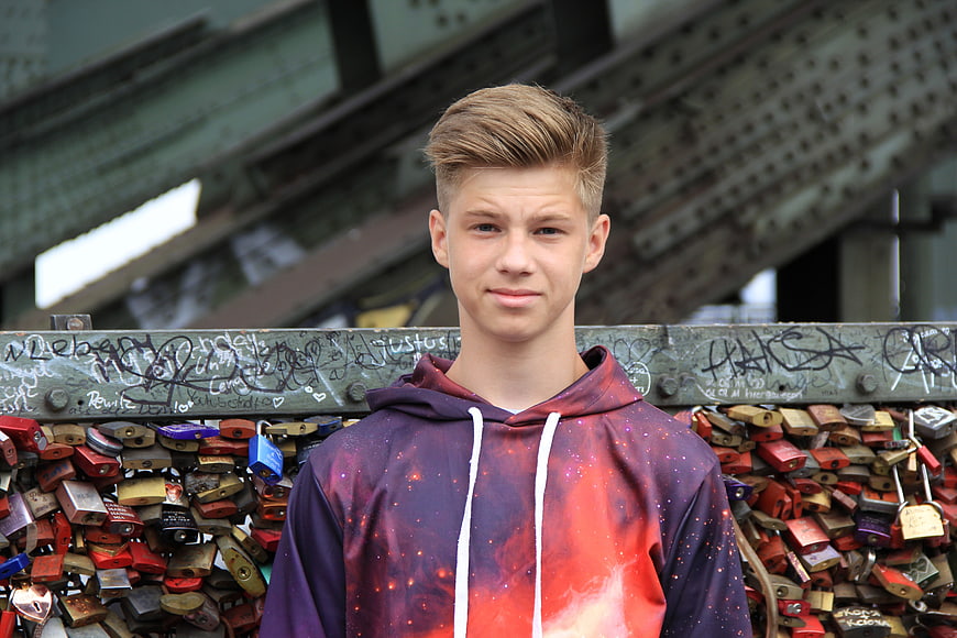 Teenage boy portrait in front of love locks on bridge