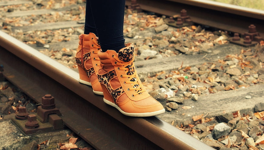 Woman balancing on railroad tracks in orange leopard print boots