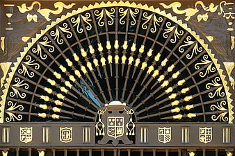 Ornate black and gold wrought iron gate with heraldic shields