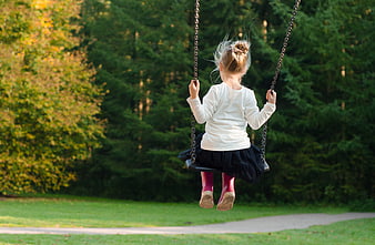 Little girl swinging in autumn park