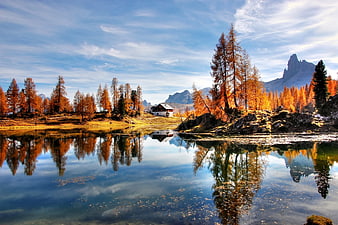 Autumn landscape with golden larch trees and lake reflection in the Dolomites