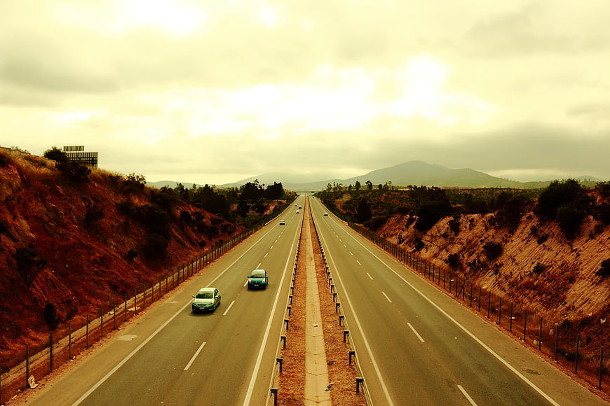 Wide highway stretching through arid landscape with mountains