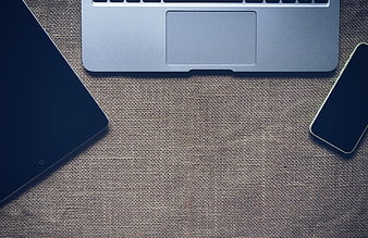 Flat lay of laptop, tablet, and smartphone on burlap texture