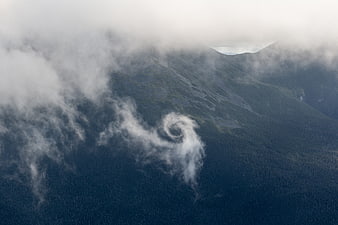 Aerial View of Mountain Forest with Swirling Clouds