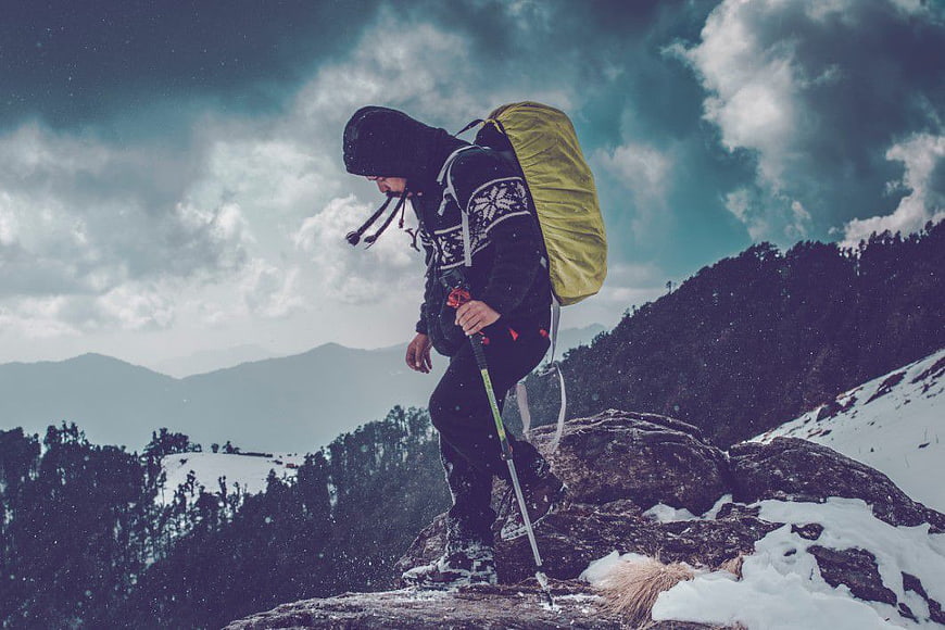 Hiker with Backpack on Snowy Mountain Peak