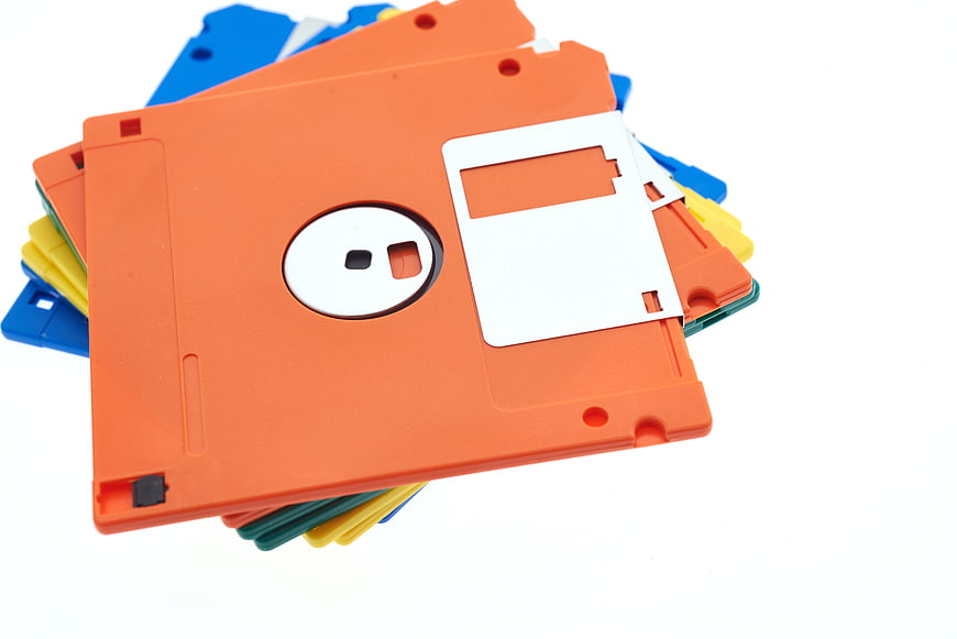 Stack of colorful vintage floppy disks on white background
