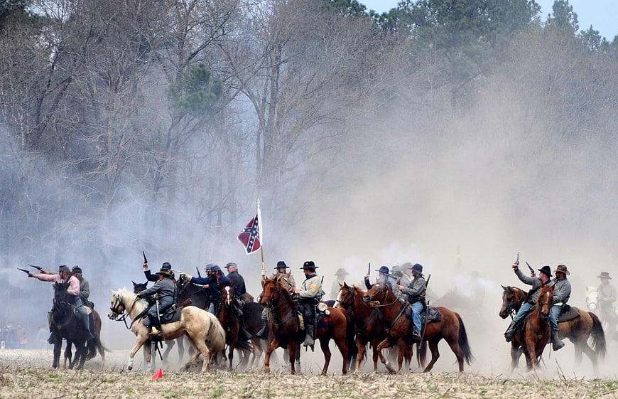 Civil War reenactment cavalry charge with smoke and flag