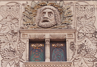 Art Nouveau stone facade with grotesque face and grape motifs