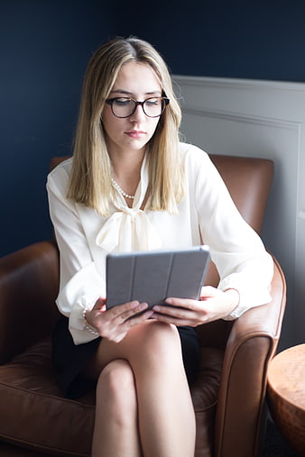 Professional woman with glasses using tablet in leather chair