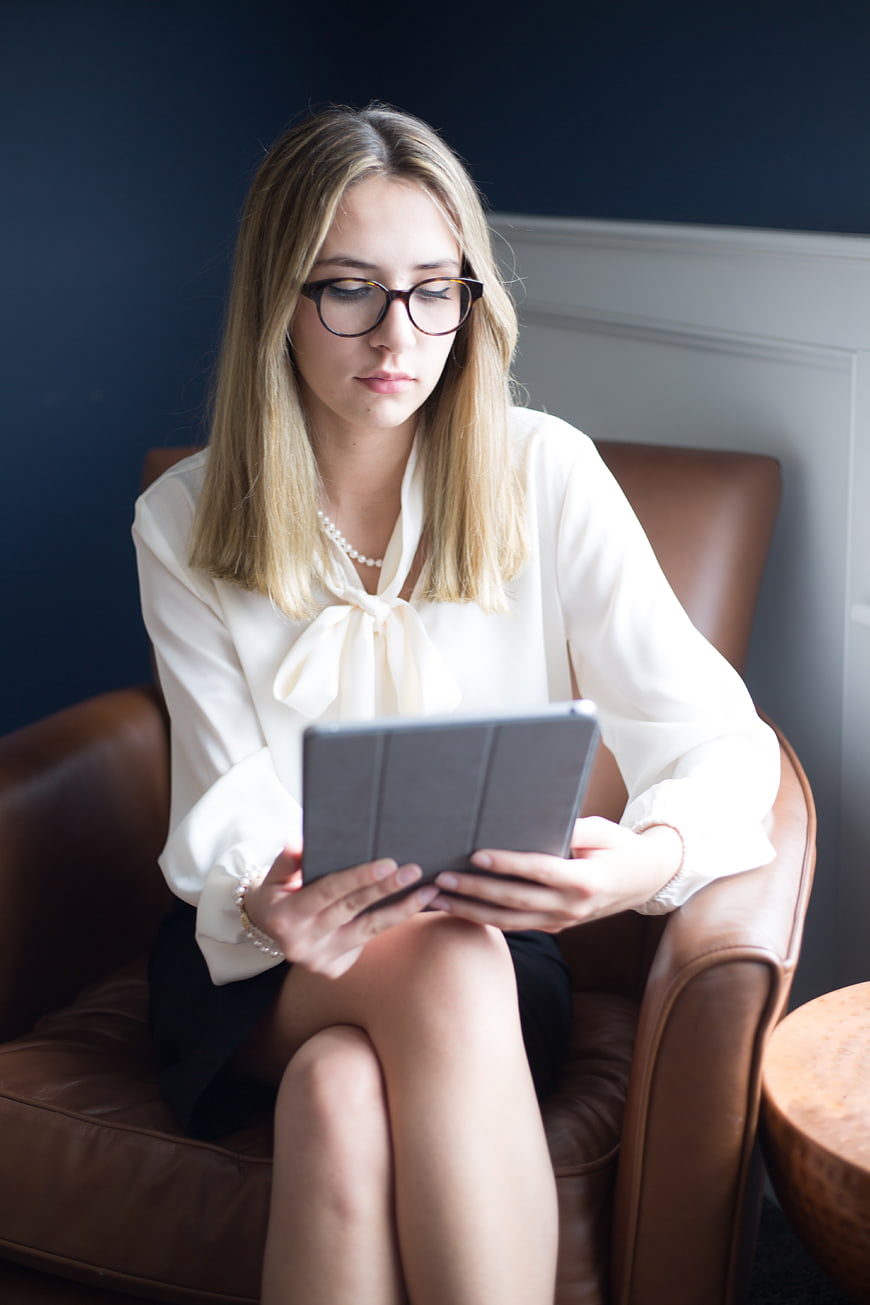 Professional woman with glasses using tablet in leather chair