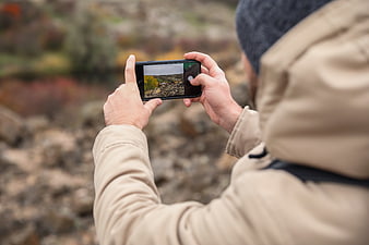 Man taking photo of autumn landscape with smartphone