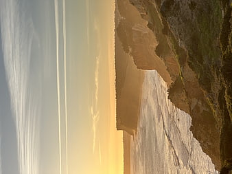 Vertical Sunset Over Coastal Cliffs and Ocean Horizon