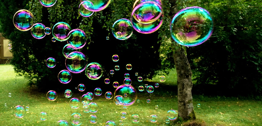 Iridescent soap bubbles floating in a green garden