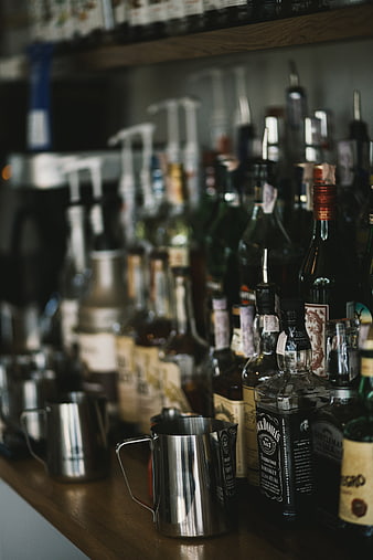 Close-up of whiskey bottles and metal shaker on bar counter