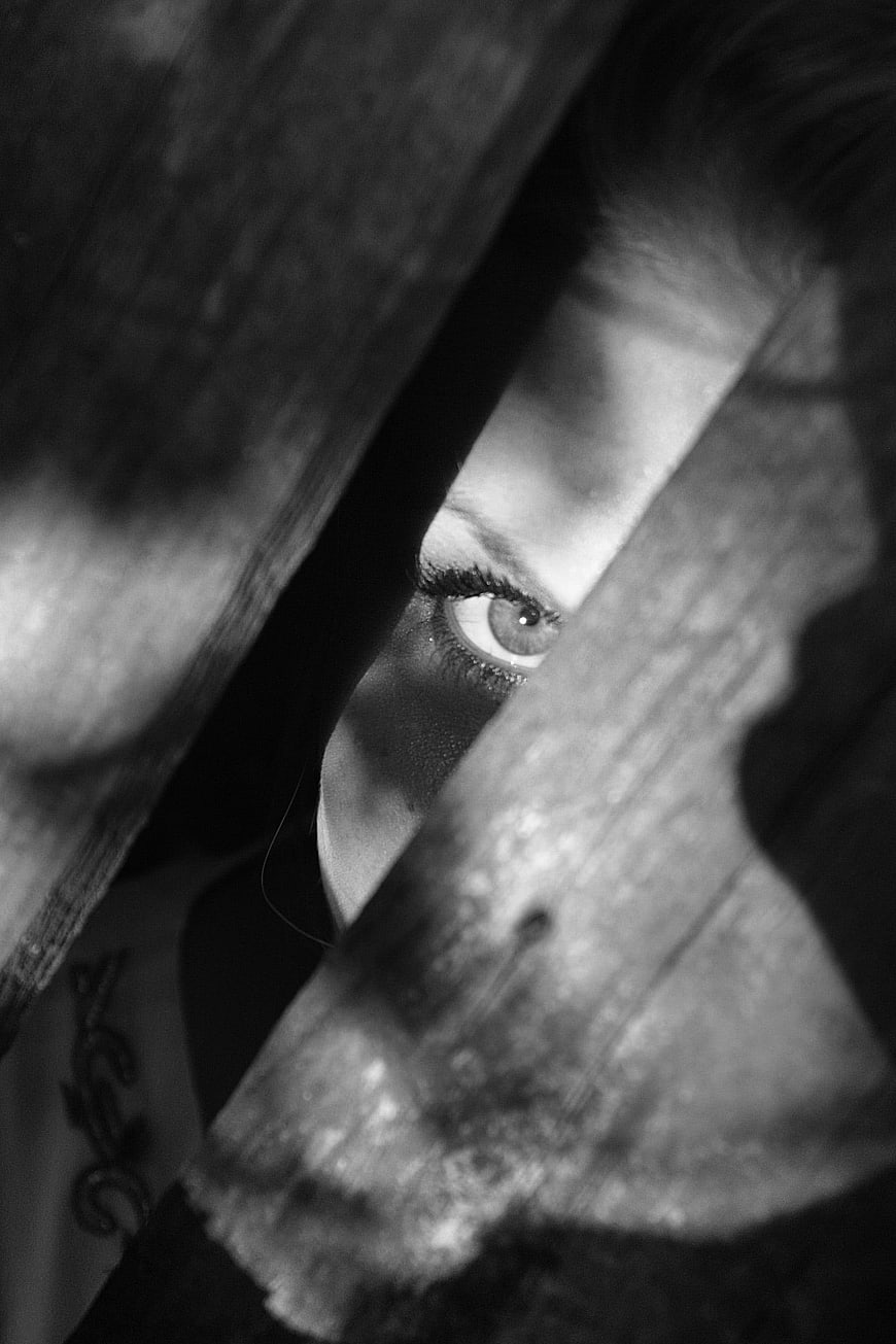Woman's Eye Peeking Through Wooden Slats in Black and White