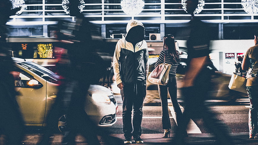 Anonymous Hooded Man Standing in Busy Night City Street