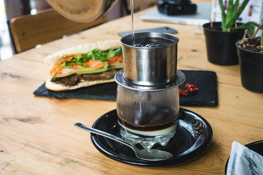 Vietnamese drip coffee brewing with condensed milk and banh mi