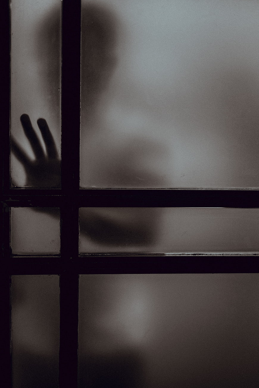 Silhouette of person behind frosted window pane