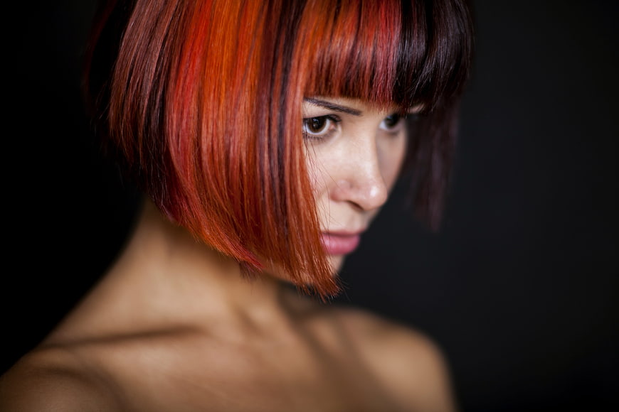 Close-up portrait of a woman with short red hair and bangs