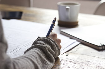 Hand sketching wireframes on desk with coffee and notebook